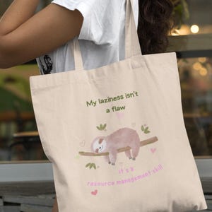 May include: A beige tote bag with a sloth illustration and the text "My laziness isn't a flaw, it's a resource management skill".