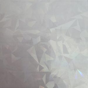 May include: A sheet of iridescent, geometric patterned paper. The design features a repeating pattern of irregular, multi-faceted shapes in shades of white and silver, with hints of rainbow iridescence.