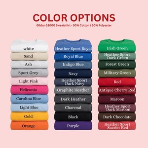 May include: A color chart for Gildan 18000 sweatshirts, 50% cotton and 50% polyester. Three vertical stacks of folded sweatshirts display various colors including white, sand, ash, grey, pink, blue, gold, orange, navy, black, purple, green, red, maroon, and brown.