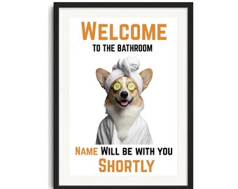 May include: Framed print with a white background featuring a Corgi wearing a spa towel and cucumber slices over its eyes. The text "WELCOME TO THE BATHROOM" and "NAME WILL BE WITH YOU SHORTLY" are in orange and black.