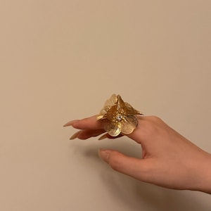 Anillo llamativo con diseño floral dorado, ajustable, joyería que no pasa desapercibida.