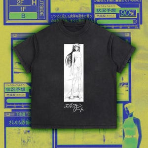 May include: Dark gray t-shirt featuring a black and white anime-style illustration of a person wrapped in bandages. The shirt has Japanese text below the illustration and is set against a colorful background.