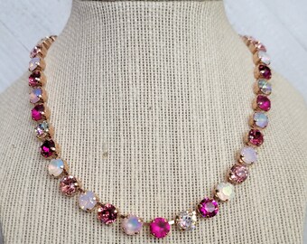 May include: A rose gold necklace with a gradient of pink, white, and clear crystals. The necklace is made of small round crystals that are set in a rose gold chain.