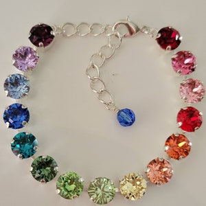 May include: A silver bracelet with a rainbow of colored crystal beads. The bracelet has a lobster clasp closure and a small blue crystal charm.