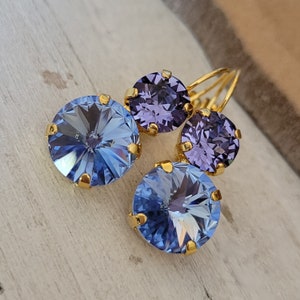 May include: A pair of gold earrings with three round blue and purple rhinestones. The earrings are dangling and have a simple design.