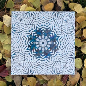 May include: A white and blue mandala design with a geometric pattern. The mandala is surrounded by a white border.