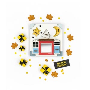May include: A wooden shape sorter toy with a house design, featuring a red door, blue windows, and star, moon, and triangle shapes. The image includes yellow gift boxes, autumn leaves, and confetti. A black sign reads "BLACK FRIDAY."