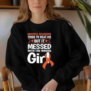 May include: Black sweatshirt with the text "Multiple Sclerosis Tried to Beat Me But It Messed With the Wrong Girl" and an orange ribbon.