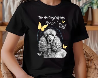 Könnte beinhalten: Schwarzes T-Shirt mit einer weißen Pudel-Illustration, dem Text "No Autographs, Please!" und gelben und weißen Schmetterlingen. Der Pudel befindet sich in einem blauen Glitzerkreis.