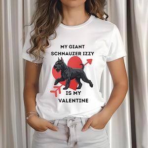 May include: White t-shirt with the text "MY GIANT SCHNAUZER IZZY IS MY VALENTINE". The graphic features a black Schnauzer dog with a red heart and arrow design. The shirt is a casual style.
