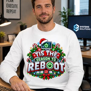 May include: A white long-sleeve sweatshirt featuring a colorful graphic print of a computer monitor wearing a Santa hat, surrounded by holly, candy canes, and Christmas lights, with the text 'TIS THE SEASON TO REBOOT' and keyboard keys.