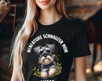 May include: Black t-shirt featuring a graphic of a Miniature Schnauzer with the text "MINIATURE SCHNAUZER MOM" and the name "LUCAS" in white. The design includes gold sparkles and green leaves, creating a charming pet-themed design.