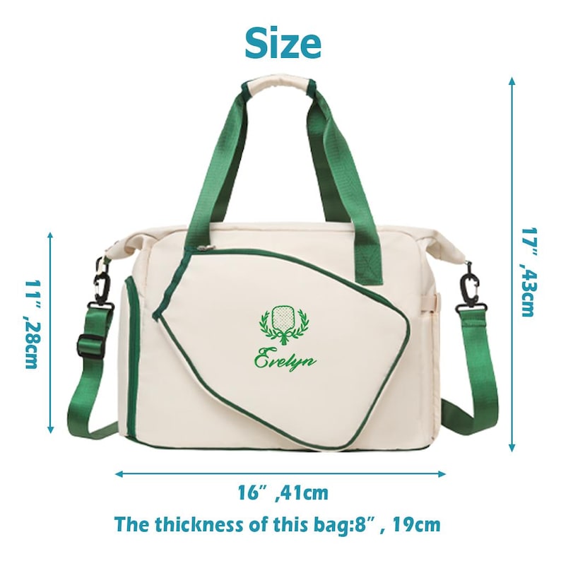 Op de afbeelding: Cr&egrave;mekleurige draagtas met groene accenten, handvatten en schouderriem. De tas heeft een geborduurd embleem en de naam "Evelyn". Afmetingen: 41 cm breed, 28 cm hoog, 43 cm diep en 19 cm dik.