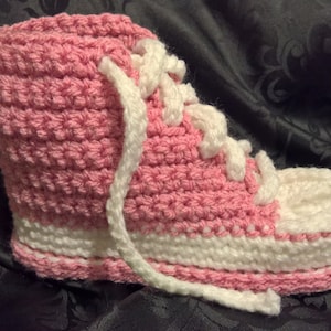 Op de afbeelding: Roze en witte gehaakte pantoffel in de vorm van een hoge sneaker.