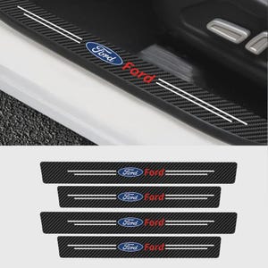 May include: Black carbon fibre car door sill protectors featuring the Ford logo in blue and red. The protectors have two white parallel stripes and the word "Ford" in red. The image also shows the car door.