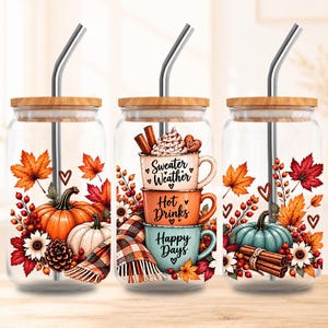 Puede incluir: Tres vasos de cristal transparente con tapas de bambú y pajitas de metal. El izquierdo muestra calabazas, hojas y bayas. El central presenta tazas apiladas con el texto Sweater Weather, Hot Drinks, Happy Days. El derecho muestra una calabaza, hojas y ramas de canela.
