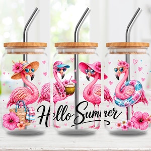 May include: Three glass tumblers with bamboo lids and stainless steel straws. Each tumbler features a pink flamingo design with sunglasses and floral accents. The words "Hello Summer" are written in black script.