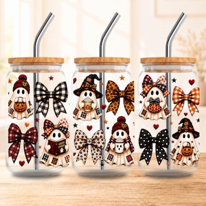 May include: Three clear glass tumblers with bamboo lids and metal straws, each featuring a repeating pattern of ghosts wearing hats, holding pumpkins or mugs, and various patterned bows, stars, and hearts in orange, black, and white colors.