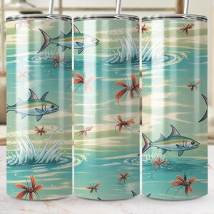 May include: A set of three stainless steel tumblers with a wraparound design featuring a serene aquatic scene. The design includes illustrations of fish, water splashes, and orange floral accents, set against a teal and cream backdrop.