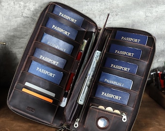 May include: Open brown leather travel wallet with multiple passport slots, card slots, and a zippered compartment. The wallet is filled with passports, cash, and coins. The wallet is open, displaying its contents.