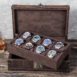 Może przedstawiać: Brązowe skórzane pudełko na zegarki z aksamitnym wnętrzem. Pudełko ma klapkę na zawiasach i zamek. Pudełko jest wypełnione 10 zegarkami, każdy z innym wzorem.