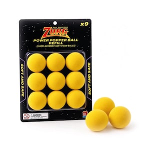 Könnte beinhalten: Eine Packung mit neun gelben weichen Schaumstoffbällen mit der Aufschrift Evil Emperor Zurg Power Popper Ball Refill vor einem schwarzen, sternenbesetzten Hintergrund. Drei weitere gelbe Schaumstoffbälle liegen vor der Verpackung, die den Text Soft and Safe sowie ein Warnsymbol für Erstickungsgefahr enthält.