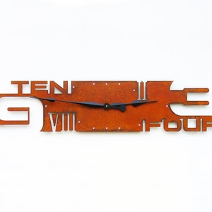 May include: A rusty metal wall clock with Roman numeral markings and the words "TEN" and "FOUR" incorporated into the design. The clock hands are black.