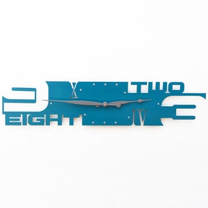 May include: A teal blue wall clock with the numbers 'one', 'two', 'three', 'four', 'five', 'six', 'seven', 'eight', 'nine', 'ten', 'eleven', and 'twelve' incorporated into the design. The clock hands are silver.