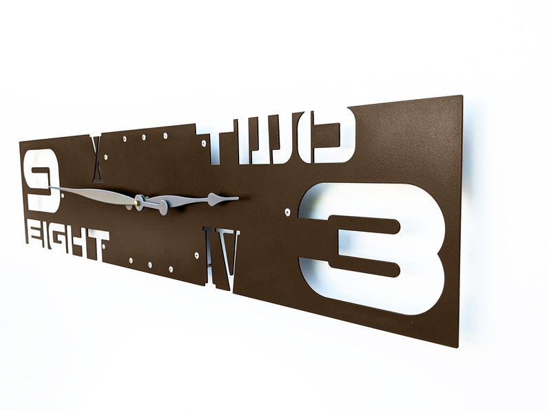 May include: A brown metal wall clock with white Roman numeral and Arabic numeral hour markers. The clock face is surrounded by the words "FIGHT" and "TWO". The clock hands are silver.