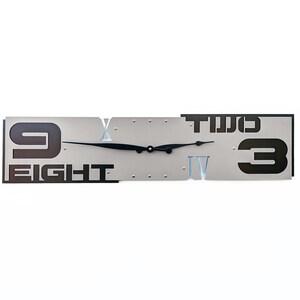 May include: A modern wall clock with a silver face and black Roman numeral markings. The clock is divided into three sections, with the numbers "9 EIGHT", "TWO", and "3" displayed in black on a silver background.