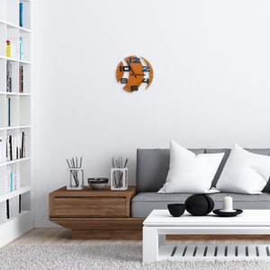 May include: A modern living room with a white bookshelf, a gray sofa with white pillows, a wooden coffee table, and a unique orange clock on the wall.