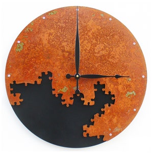 May include: A round, rusty orange metal clock with black hands and a black background. The clock face is made up of puzzle pieces, with some pieces missing.