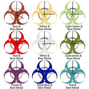 May include: Nine biohazard symbol clocks in different colors, including rust, yellow, light green, red, white, dark green, purple, royal blue, and teal. Each clock has a black minute hand and a silver hour hand.