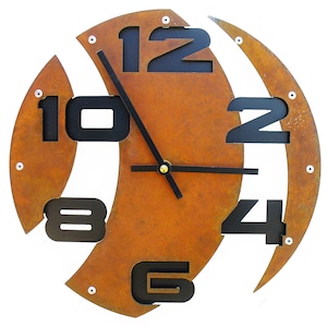 May include: A rusty metal clock with black numbers and hands. The clock face is divided into sections, with each number appearing in a different section. The clock is approximately 12 inches in diameter.
