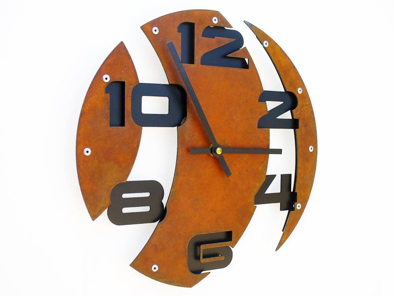 May include: A rusty orange metal wall clock with black numbers and hands. The numbers are arranged in a unique, asymmetrical pattern.