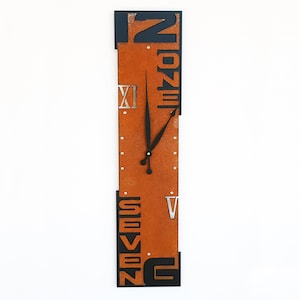 May include: A vertical orange and black clock with Roman numeral markings and the words "Twelve" and "Seven" on the face.