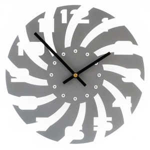 May include: Gray and white clock with a unique design. The numbers are cut out of the gray background and the clock hands are black.