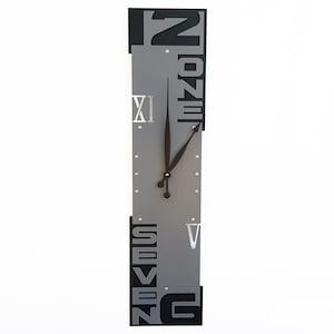 May include: A gray and black wall clock with Roman numeral markings and the words "Twelve" and "Seven" on the sides. The clock hands are black.