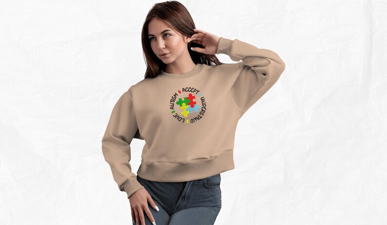 May include: A tan sweatshirt with a colorful puzzle piece design and the words "Love, Understand, Accept, Autism" around the puzzle pieces.