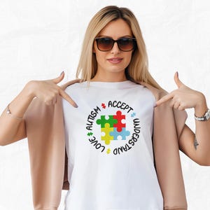 May include: A white t-shirt with a colorful puzzle piece design and the words "Love, Understand, Accept, Autism" around the puzzle piece.