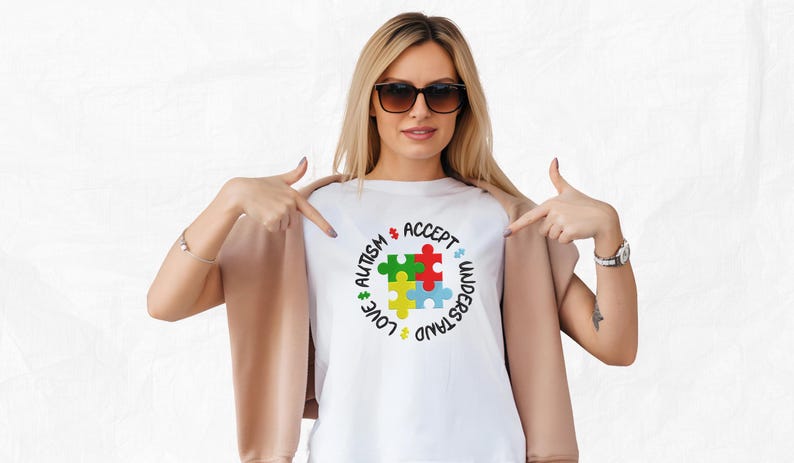 May include: A white t-shirt with a colorful puzzle piece design and the words "Love, Understand, Accept, Autism" around the puzzle piece.