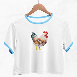 May include: White cropped t-shirt with a blue trim around the neckline. The shirt features a colorful rooster illustration.