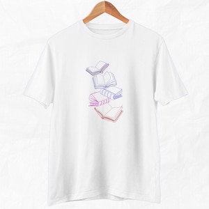 May include: White t-shirt with a graphic of a stack of books in a gradient of pink and blue.