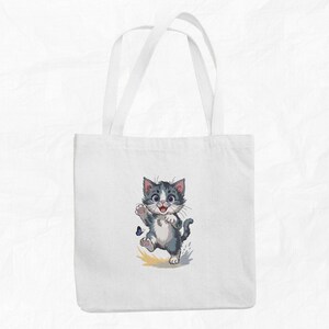 May include: White tote bag with a cartoon image of a grey and white kitten chasing a blue butterfly. The kitten is smiling and has its paw raised. The bag has two white handles.