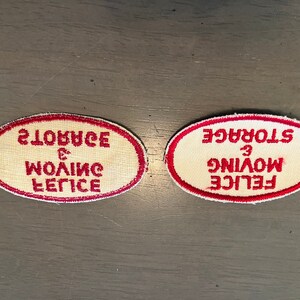 May include: Two white oval fabric patches with red borders. The text on the patches reads "FELICE MOVING & STORAGE" in a mirrored font.