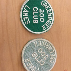May include: Two round green and white embroidered patches with the text "Greenbrier Club 200 Lanes" on them.