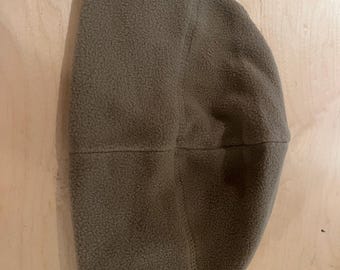 Puede incluir: Un gorro de lana polar marrón. El gorro está hecho de un material suave y texturizado y tiene un diseño simple y clásico. El gorro es de color liso y parece cálido y cómodo.