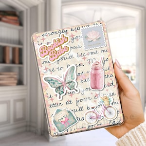 May include: A clear phone case with a collage design. The design includes stickers with text that says "Bookish Babe", a butterfly, a pink bicycle, and a pink milkshake. The background has handwritten script.