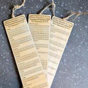 May include: Three wooden Bible Reader's Log bookmarks with twine attached. Each bookmark has a different section of the Bible listed, including Old Testament and New Testament. The bookmarks are light brown with dark brown text.