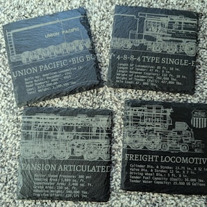 May include: Four square black slate coasters featuring detailed white line drawings of Union Pacific Big Boy locomotives. Each coaster displays technical specifications, including locomotive dimensions, weights, and mechanical data in imperial units.